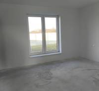 4 izbový rodinný  dom v obci Michal na Ostrove! - Prázdna izba v rodinnom dome s veľkým oknom a nedokončenou podlahou.