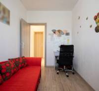 Znížená cena za 4 izbový rodinný dom v obci Jahodná - Útulná miestnosť s červenou pohovkou, stolom, čiernou stoličkou v rodinnom dome.