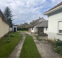 Znížená Cena!Na predaj rodinný dom vo Vrakúni, blízko Dunajskej Stredy - Dvor rodinného domu vo Vrakúni s trávnikom a vonkajšími prístavbami.