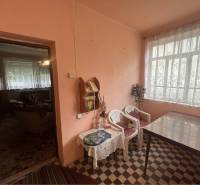 Znížená Cena!Na predaj rodinný dom vo Vrakúni, blízko Dunajskej Stredy - Interiér rodinného domu so stolom, plastovými stoličkami a závesmi na okne.