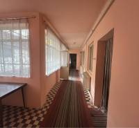 Znížená Cena!Na predaj rodinný dom vo Vrakúni, blízko Dunajskej Stredy - Rodinný dom má chodbu s kobercom, oknami so záclonami a stolom.