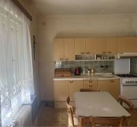 Znížená Cena!Na predaj rodinný dom vo Vrakúni, blízko Dunajskej Stredy - Kuchyňa v rodinnom dome s plynovým sporákom, jedálenským stolom a záclonami.