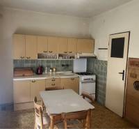 Znížená Cena!Na predaj rodinný dom vo Vrakúni, blízko Dunajskej Stredy - Kuchyňa v rodinnom dome s retro nábytkom a stoličkami, podlaha s dreveným dekorom.