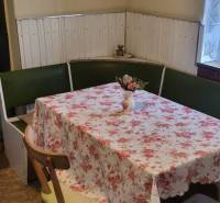 Na predaj starší rodinný dom v obci Ohrady - Jedáleň rodinného domu s rohovou lavicou, kvetinovým obrusom a dekoráciou na stene.