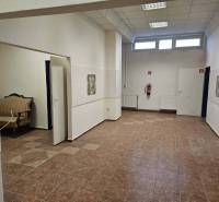 Exkluzívny obchodný priestor na prenájom v centre Dunajskej Stredy – u - Obchodné priestory s dlažbou, bielymi stenami, sedačkou a vysokým stropom.