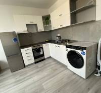 Na prenájom štýlový a moderný 2 izbový byt v centre Dunajskej Stredy - Kuchyňa s bielymi skriňami, spotrebičmi a podlahou s dreveným dekorom v 2-izbovom byte.