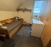 Predaj rodinného domu, Dunajská Streda - Detská izba s posteľou, hračkami, skrinkou a podlahou s dreveným dekorom v rodinnom dome.