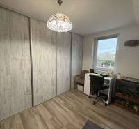 Predaj rodinného domu, Dunajská Streda - Izba v rodinnom dome s pracovným stolom, podlahou s dreveným dekorom a vstavanými skriňami.