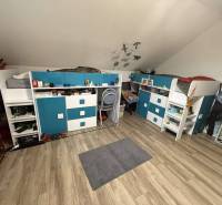 Predaj rodinného domu, Dunajská Streda - Izba v rodinnom dome s podlahou s dreveným dekorom, poschodovými posteľami a pracovnými stolmi.