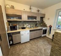 Predaj rodinného domu, Dunajská Streda - Kuchyňa v rodinnom dome s keramickou podlahou a drevenými skrinkami.