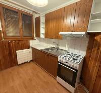 Prenájom 3-izbového bytu, Dunajská Streda - Kuchyňa v 3-izbovom byte s plynovým sporákom, drevenými skrinkami a podlahou s dreveným dekorom.