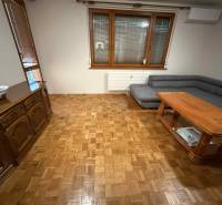 Prenájom 3-izbového bytu, Dunajská Streda - Obývacia izba v 3-izbovom byte s podlahou s dreveným dekorom, sedačkou a stolom.