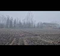 Pozemok-Bohelov - Hmlistá krajina v Boheľove s oranicou, stromami a budovou ako súčasť zvláštnych nehnuteľností.