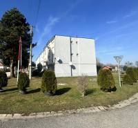 ☎️ 0918197701-Predám 3 izbový byt s loggiou po kompletnej rekonštrukci - Bytovka v Dolnom Štále obklopená zeleňou a upravenými kríkmi na modrej oblohe.