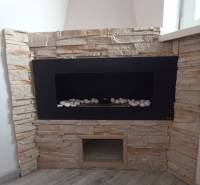 ☎️ 0918197701-Predám 3 izbový byt s loggiou po kompletnej rekonštrukci - Interiér 3-izbového bytu s krbom obloženým kamennými tvárnicami a podlahou s dreveným dekorom.