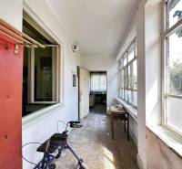 ☎️ 0918197701- Na predaj starší rodinný dom vhodný na kompletnú presta - Chodba v rodinnom dome s oknami, stolom a chodítkom, ukazuje opotrebované steny.