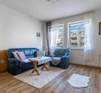 ☎️ 0918197701- PREDAJ - Nebytových priestorov Dunajská Streda - Obývacia izba s modrou sedačkou a podlahou s dreveným dekorom.