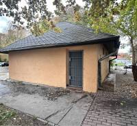 ☎️ 0918197701- Znížená cena     Predaj – Obchodný priestor v Dunajskej - Budova s plechovými dverami obklopená stromami a zaparkovanými autami v Dunajskej Strede.