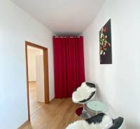 ☎️ 0918197701   Na predaj  elegantný 3 izbový byt priamo v centre Duna - Izba v 3-izbovom byte s podlahou s dreveným dekorom, červenými závesmi a kreslami.