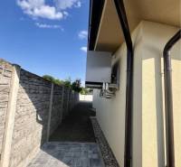 Jedinečný 5 izbový dom na predaj v TOP lokalite-GARDEN TOWN - Rodinný dom v GARDENTOWN, Dunajská Streda s chodníkom vedľa múru a modrou oblohou.