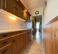 Na predaj: CENTRUM veľký 3 izb.byt + BALKON + ŠATNIK - Kuchyňa s drevenou kuchynskou linkou, obklady a 3-izbový byt vidieť v pozadí.