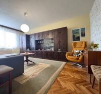 Na predaj: CENTRUM veľký 3 izb.byt + BALKON + ŠATNIK - Obývačka v 3-izbovom byte s rustikálnym nábytkom, drevenou podlahou a pohodlným kreslom.