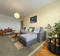 Na predaj: CENTRUM veľký 3 izb.byt + BALKON + ŠATNIK - Opis obývacej izby, sivý gauč, rastliny, vzorovaná tapeta, koberce, atmosféra a 3-izbový byt.