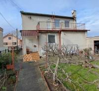 NA PREDAJ 6 izbový rodinný dom v obci Hrušovany  - Rodinný dom v Hrušovanoch so záhradou, upravenými stromami a garážou.