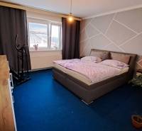 NA PREDAJ 6 izbový rodinný dom v obci Hrušovany  - Spálňa v rodinnom dome s modrým kobercom, posteľou a rotopedom.