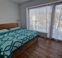 Rekreačný apartmán Vys. Tatry- HREBIENOK RESORT I. - 92 m2 -3-izbový - Spálňa v rekreačnom apartmáne s posteľou, balkónom a podlahou s dreveným dekorom.
