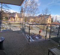Rekreačný apartmán Vys. Tatry- HREBIENOK RESORT I. - 92 m2 -3-izbový - Balkón rekreačného apartmánu s výhľadom na kostol a architektúru v Starom Smokovci, Vysoké Tatry.
