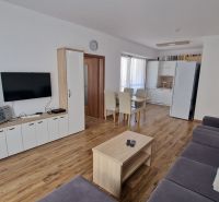 Rekreačný apartmán Vys. Tatry- HREBIENOK RESORT I. - 92 m2 -3-izbový - Obývacia izba rekreačného apartmánu s televízorom, sedačkou, jedálenským stolom a podlahou s dreveným dekorom.