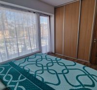 Rekreačný apartmán Vys. Tatry- HREBIENOK RESORT I. - 92 m2 -3-izbový - Spálňa v rekreačnom apartmáne s veľkými oknami a posteľou, podlaha s dreveným dekorom.