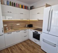 Rekreačný apartmán Vys. Tatry- HREBIENOK RESORT I. - 92 m2 -3-izbový - Kuchyňa v rekreačnom apartmáne s bielymi skrinkami a podlahou s dreveným dekorom.