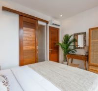 PREDAJ 3KK Investičná zariadená vila s bazénom BALI-Canggu Padonan - Izba vo vile s dreveným dekorom, prúteným nábytkom a rastlinou, ponúka útulnosť.