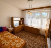  3 izbový byt s balkónom 75m2 Zvolen - Západ - Izba s posteľou a skriňou v 3-izbovom byte s kvetinovým kobercom.