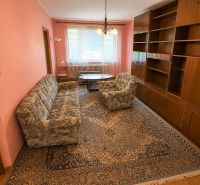  3 izbový byt s balkónom 75m2 Zvolen - Západ - Obývačka v 3-izbovom byte s ružovými stenami, vzorovaným kobercom a drevenými skrinkami.