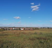 INVESTIČNÝ POZEMOK, ŠENKVICE - Šenkvice obklopené poľnohospodárskymi a lesnými pozemkami pod jasnou modrou oblohou.