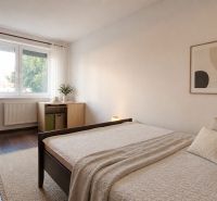 Bývanie s vlastnou predzáhradkou – zariadený 2-izbový byt (62+33 m²) - Spálňa v 2-izbovom byte s oknom, postelí a podlahou s dreveným dekorom.