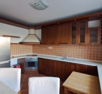 Bývanie s vlastnou predzáhradkou – zariadený 2-izbový byt (62+33 m²) - Kuchyňa s drevenými skrinkami a spotrebičmi v 2-izbovom byte, podlaha s dreveným dekorom.