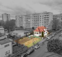Rodinný dom s pozemkom 727m2, Tatranská ul. - Trenčín - Rodinný dom na Tatranskej ulici v Trenčíne obklopený záhradou, s výškovými budovami v pozadí.