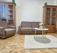 Predaj dvojizbový byt v Banskej Štiavnici, pod Kalváriou - Obývacia izba v 2-izbovom byte s pohodlným gaučom, konferenčným stolíkom a podlahou s dreveným dekorom.