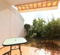Chorvátsko, Vodice - zariadený bungalov, výhľad na more - Terasa rodinného domu vo Vodiciach so stolíkom, stoličkou a výhľadom na záhradu.