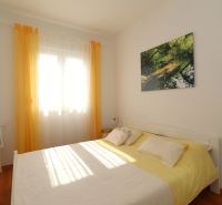 Chorvátsko, Vodice - zariadený bungalov, výhľad na more - Spálňa v rodinnom dome s posteľou, kreslom a podlahou s dreveným dekorom.