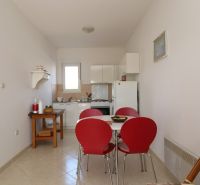Chorvátsko, Vodice - zariadený bungalov, výhľad na more - Jedáleň s červenými stoličkami a bielou kuchyňou v rodinnom dome.
