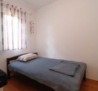 Chorvátsko, Vodice - zariadený bungalov, výhľad na more - Jednoduchá spálňa s posteľou, podlahou s dreveným dekorom a svetlými závesmi.