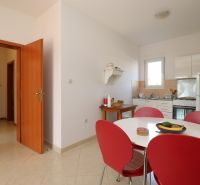Chorvátsko, Vodice - zariadený bungalov, výhľad na more - Jedáleň so stolom a červenými stoličkami v rodinnom dome, svetlá dlažba.