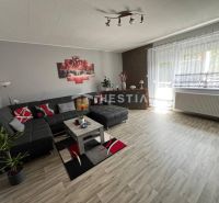 NOVINKA Priestranný 3-izbový byt (99 m²) s pozemkom, terasou, 2 balkón - Priestranná obývačka v 3-izbovom byte s podlahou s dreveným dekorom a pohodlnou sedacou súpravou.