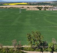 Trhovište – 5.894 m2 POZEMOK na mobilný dom so stavebným potenciálom  - Zelené Rekreačné pozemky pri Trhovišti s výhľadom na dedinu a žlté polia.