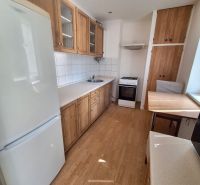 NA PRENÁJOM 1 IZBOVÝ TEHLOVÝ BYT, 34 M2, KOŠICE - ŠACA - Kuchyňa v 1-izbovom byte s bielymi stenami, podlahou s dreveným dekorom a spotrebičmi.